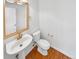 Clean half bathroom featuring pedestal sink, golden hardware, and hardwood flooring at 1491 Ophir Rd, Castle Rock, CO 80109
