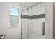 Updated shower with white tile, black mosaic accents, glass door and a window at 20445 Mitchell Pl, Denver, CO 80249