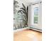 A bright, well-lit living room with hardwood floors, tropical wallpaper, and a large window with sheer white curtains at 2098 N Clarkson St, Denver, CO 80205