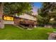 Landscaped backyard with a spacious lawn, charming deck, and mature trees, perfect for relaxation at 7308 S Steele Cir, Centennial, CO 80122