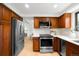 Well-lit kitchen features stainless steel appliances, wood cabinetry, and quartz countertops at 7308 S Steele Cir, Centennial, CO 80122