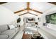 Bright living room with vaulted ceilings, wooden beams, a skylight, comfortable seating, and an open view into the kitchen at 7308 S Steele Cir, Centennial, CO 80122