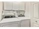 Efficient laundry room with modern white washer and dryer, upper cabinets, and a hanging rack at 7440 S Blackhawk St # 2-106, Englewood, CO 80112