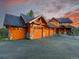 Expansive three-car garage with carriage doors and stone accents at dusk at 29590 Buchanan Dr, Evergreen, CO 80439