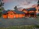 Exterior of a log home featuring a spacious driveway and three-car garage with wooden doors at 29590 Buchanan Dr, Evergreen, CO 80439