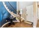 Elegant foyer featuring a curved staircase with iron railings, hardwood floors, and a striking blue accent wall at 12740 W 73Rd Pl, Arvada, CO 80005