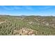 Expansive aerial view showcasing a luxurious home surrounded by lush forest and rolling mountains with snow capped peaks at 12555 Critchell Ln, Littleton, CO 80127