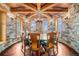 The dining room features a stone wall design with a wooden ceiling and a large round table at 12555 Critchell Ln, Littleton, CO 80127