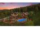 Aerial view of a luxurious home with a pool and beautiful landscaping surrounded by lush greenery at dusk at 12555 Critchell Ln, Littleton, CO 80127