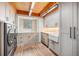 Well-lit laundry room with stainless steel washer/dryer, sink, and wood cabinets at 12555 Critchell Ln, Littleton, CO 80127