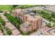 Brick condo building featuring balconies, patio, and roof deck is surrounded by trees and has a parking area at 2400 E Cherry Creek South Dr # 207, Denver, CO 80209