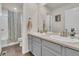 Modern bathroom with dual sinks, gray cabinets, large mirror, and a shower with floral curtain at 4884 St Vrain Rd, Firestone, CO 80504