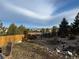 Landscaped backyard with mature trees, a wooden fence, and a view of the neighborhood at 2447 Fairway Wood Cir, Castle Rock, CO 80109