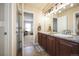 Bathroom with double sinks, dark wood vanity, decorative lighting, and a view to the bedroom at 2447 Fairway Wood Cir, Castle Rock, CO 80109