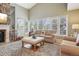Sunlit living room features a stone fireplace and a wall of windows overlooking the backyard at 1582 W Briarwood Ave, Littleton, CO 80120