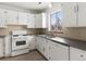 Galley kitchen with white cabinets, gas range and dishwasher at 2615 N Steele St, Denver, CO 80205