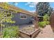 Landscaped backyard featuring raised garden beds, pea gravel, and gray siding home with white trim windows at 1338 S Fairfax St, Denver, CO 80222