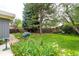 Beautiful backyard featuring green lawn, mature trees, landscaping, and flower garden at 1338 S Fairfax St, Denver, CO 80222
