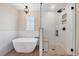 Bright bathroom with stand alone tub next to seamless glass shower featuring white subway tile and black hardware at 22898 Addington Pl, Parker, CO 80138