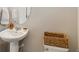 Powder room featuring pedestal sink, oval mirror, and a stylish wicker basket atop the toilet at 1954 S Poplar Ct, Denver, CO 80224