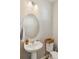 Powder room featuring pedestal sink, oval mirror, and a stylish wicker basket atop the toilet at 1954 S Poplar Ct, Denver, CO 80224