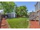 A spacious backyard with a shed surrounded by greenery, mulched areas and wood fencing at 3965 S Fundy Cir, Aurora, CO 80013