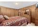 Cozy bedroom with wood paneled walls, a large dresser with mirror, and an inviting, patterned bedspread at 5960 Glencoe St, Commerce City, CO 80022