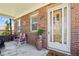 Cozy brick front porch with seating, a decorative door, and brick accents at 5960 Glencoe St, Commerce City, CO 80022