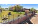 A well-maintained yard features a brick and wrought iron fence, grass, and mature foliage at 5960 Glencoe St, Commerce City, CO 80022