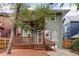 Home's back exterior features a wooden deck and porch shaded by lush trees at 1352 N Downing St, Denver, CO 80218
