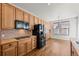 Spacious kitchen with light wood cabinets, black appliances, and tile backsplash at 958 Bramblewood Dr, Castle Pines, CO 80108