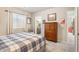 Cozy bedroom with large window, gray carpet, and decor with a rustic wood dresser and an ensuite bathroom entrance at 15773 Timber Trek Way, Monument, CO 80132