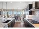 Open kitchen featuring dark cabinetry, stainless steel range hood, island seating, and a connecting dining space at 15773 Timber Trek Way, Monument, CO 80132