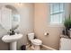Neat powder bathroom features pedestal sink, round mirror, and toilet with window at 26731 E Hinsdale Pl, Aurora, CO 80016