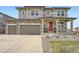 Two-story home featuring stone accents, three-car garage, covered porch and red front door at 26731 E Hinsdale Pl, Aurora, CO 80016