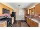 Well-lit kitchen featuring wood cabinets, tiled backsplash, and black appliances at 845 S Kenton St, Aurora, CO 80012