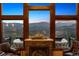 Cozy living room view showcasing the fireplace and expansive windows with stunning mountain views at 26116 Chief Hosa Rd, Golden, CO 80401