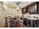 Charming wet bar with a barrel table, stone wall, and wine refrigerator at 26116 Chief Hosa Rd, Golden, CO 80401