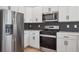 Modern kitchen features white cabinets, stainless steel appliances, and stylish backsplash at 691 N Tempe St, Aurora, CO 80018