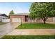 Charming brick home featuring a well-manicured lawn, mature tree, and inviting front porch at 9040 Grand Mesa Ave, Longmont, CO 80504