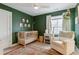 Cozy Bedroom featuring a wood crib, comfortable chair, green walls, and natural light at 2840 S Bannock St, Englewood, CO 80110