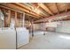 Unfinished basement with exposed beams, concrete floor and laundry hookups and storage area at 772 Urban Ct, Lakewood, CO 80401