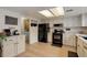 Efficient kitchen with white cabinetry, black appliances, and functional layout, adjacent to a cozy breakfast nook and laundry area at 12430 E Pacific Cir # B, Aurora, CO 80014