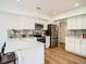 Modern white kitchen with stainless steel appliances, quartz countertops, and wood flooring at 21472 E 46Th Ave, Denver, CO 80249