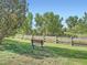 Peaceful park view with a wooden bench surrounded by lush greenery and a rustic fence at 21472 E 46Th Ave, Denver, CO 80249