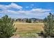 View of a spacious backyard, showcasing a large open field, mature trees, and neighborhood homes at 282 N De Gaulle St, Aurora, CO 80018