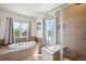 Luxurious bathroom featuring a soaking tub, separate glass-enclosed shower, and bright windows at 282 N De Gaulle St, Aurora, CO 80018