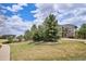 Beautifully landscaped front yard with a lush green lawn, mature trees, and stone accents, enhancing curb appeal at 282 N De Gaulle St, Aurora, CO 80018