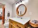 Bathroom featuring modern lighting fixtures, wood vanity, vessel sink, and a round wood-trimmed mirror at 3817 Ponderosa Dr, Evergreen, CO 80439