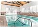 Indoor swimming pool with blue trim, natural lighting, and accessibility handrails at 3460 S Poplar St # 204, Denver, CO 80224